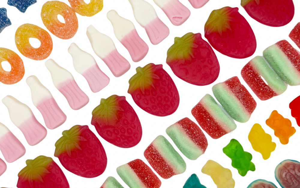 A line of sweets, strawberry, milkshake bottles, peach rings and watermelon slices sweets.